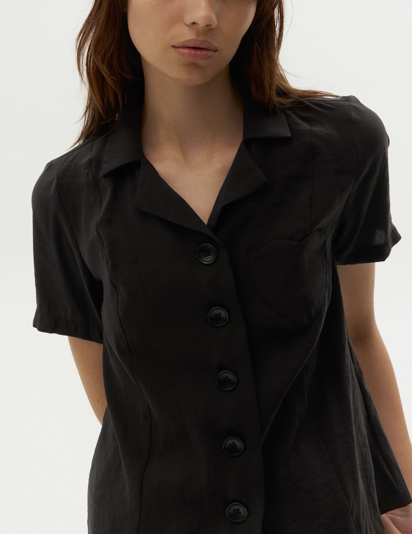 black shirt with a heart pocket, featuring a chic lapel collar, short sleeves and a straight hem. Forma clothing online. Чорна жіноча сорочка з коротким рукавом на карманом у вигляді серця від бренду ФОРМА