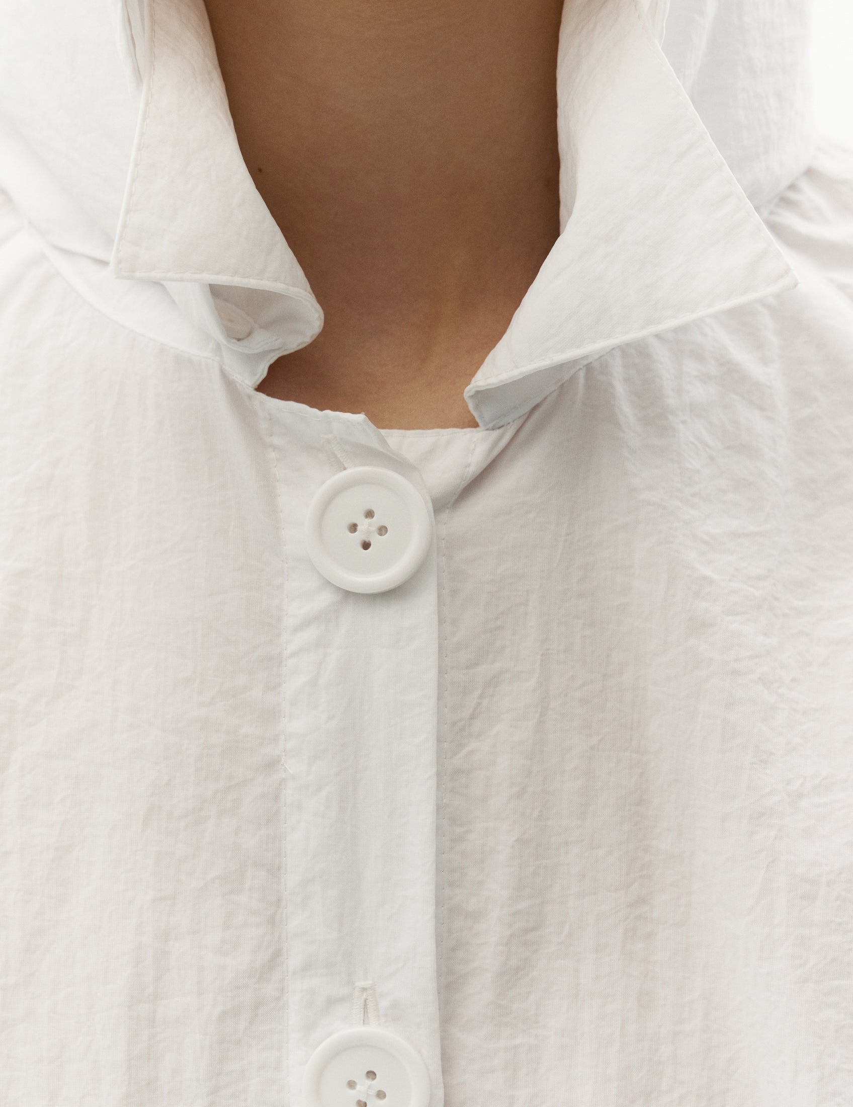 The wrinkled fabric of this waterproof white raincoat adds a unique texture, giving it a distinctive and stylish appeal. FORMA clothing brand