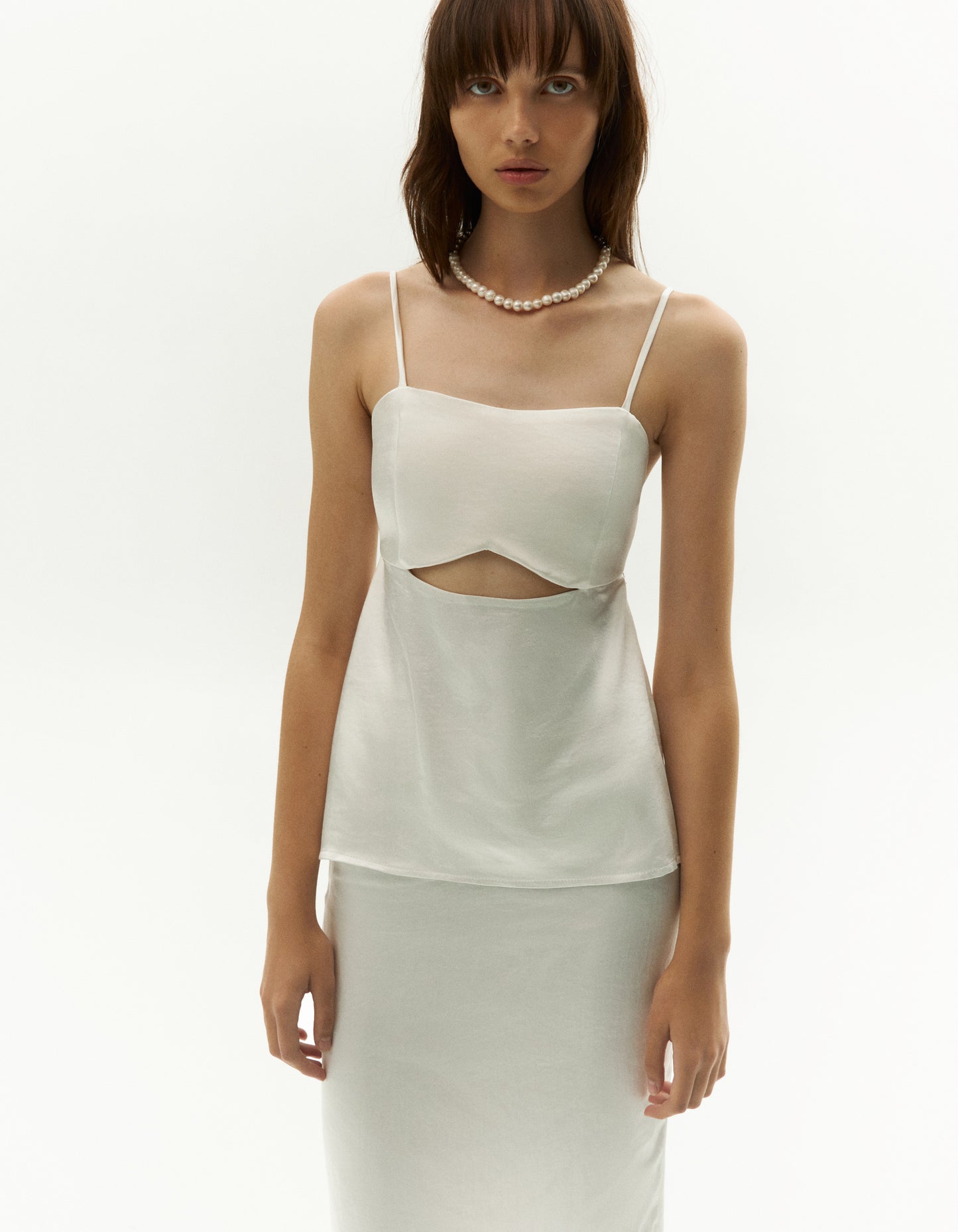 white open-back top, crafted to make a statement. This stunning piece showcases alluring front cut-out detail for a touch of contemporary flair. For a sophisticated ensemble, pair it with our satin finish long skirt, creating a chic suit-inspired look that exudes elegance. Embrace the fusion of modernity and grace with this impeccably coordinated set. Leave a lasting impression wherever you go with this fashion-forward combination.